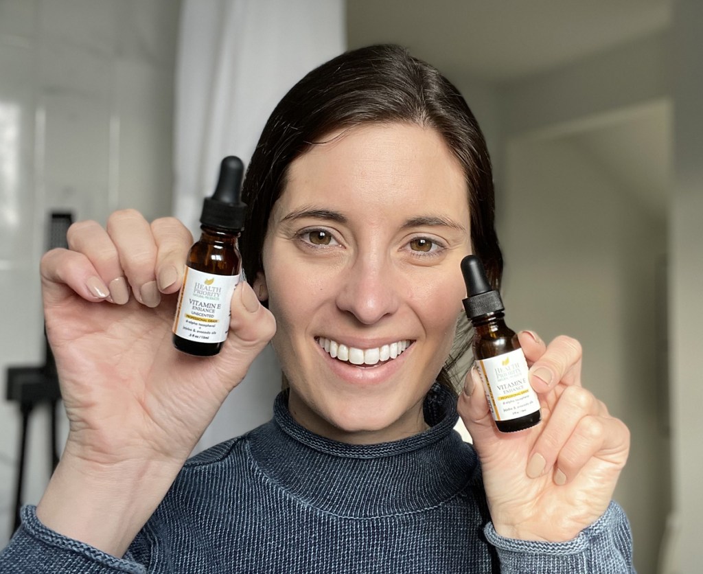 woman holding up two bottles of vitamin e oil