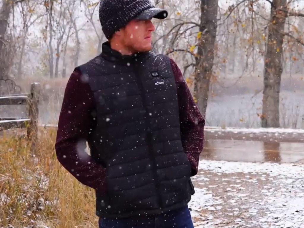 Man standing outside in snow, wearing black heated vest
