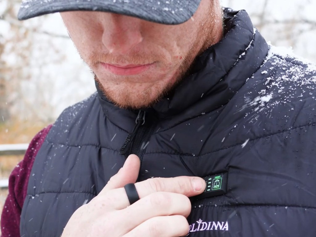 Man, pushing temperature control button on black heated vest