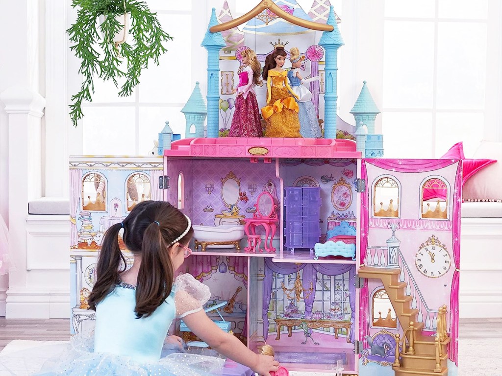 girl sitting on floor playing with KidKraft Disney Princess Dance & Dream Dollhouse