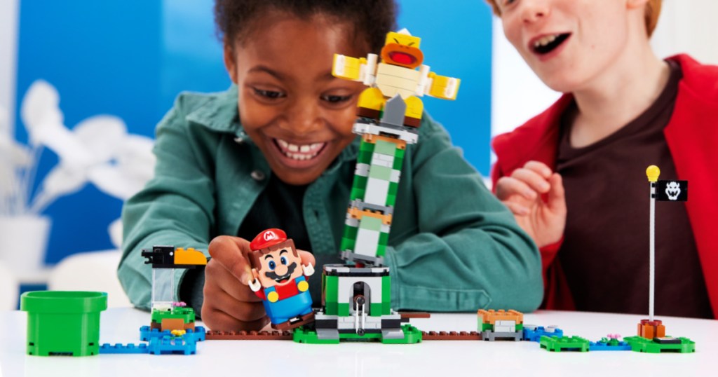 Kid holding a LEGO Super Mario and tipping over a tower