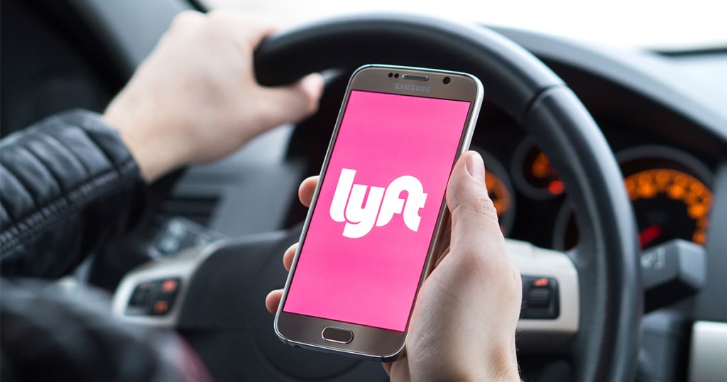 person holding phone with lyft app in car