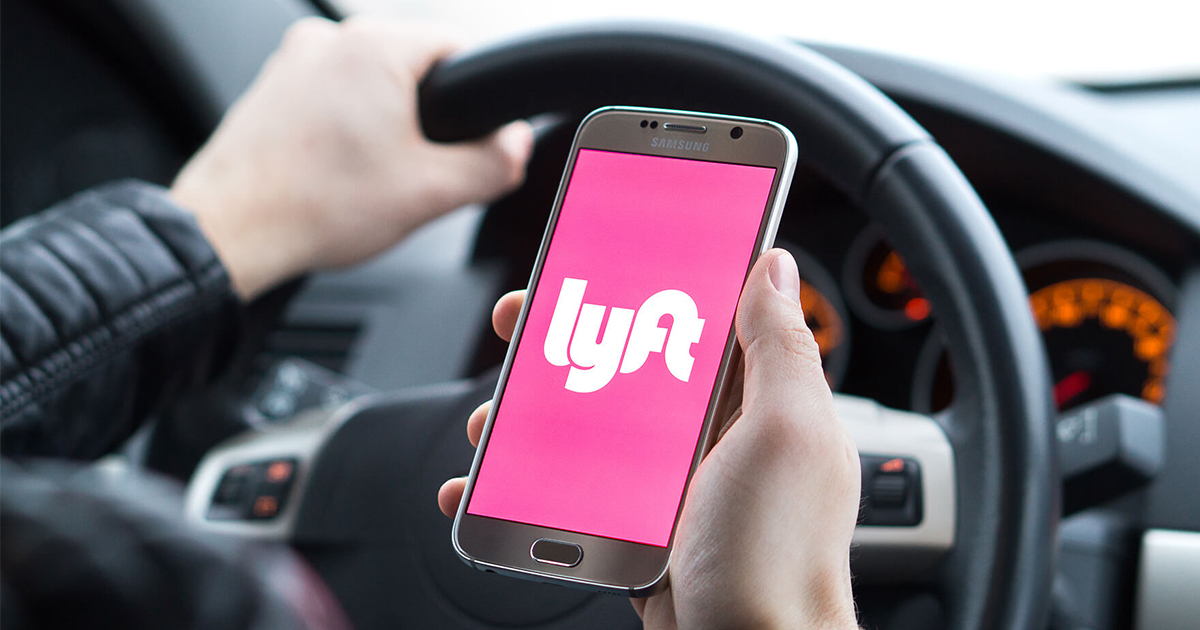 person holding phone with Lyft app in car