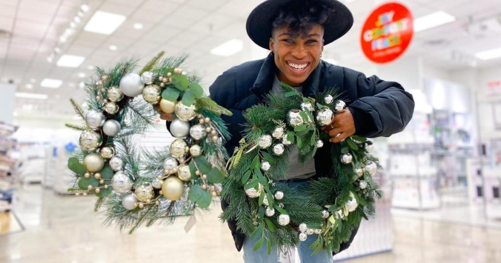 woman holding north pole trading co christmas wreaths in store