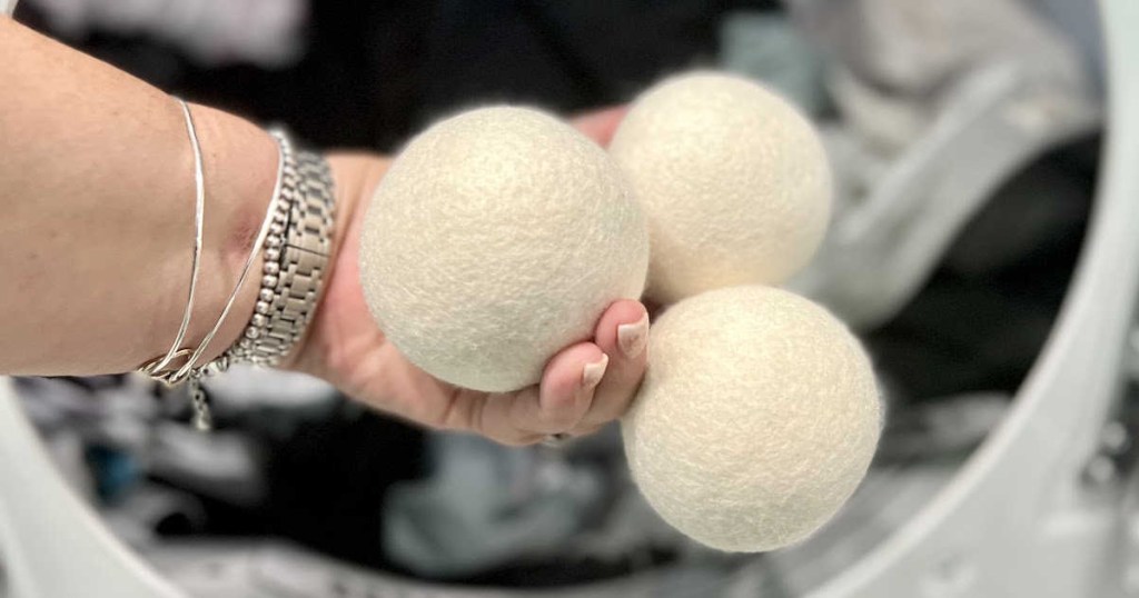 woman holding sustainable products and eco friendly products wool dryer balls in laundry room