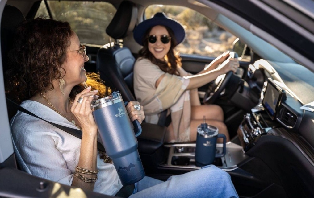 two women in a car with a Stanley tumbler