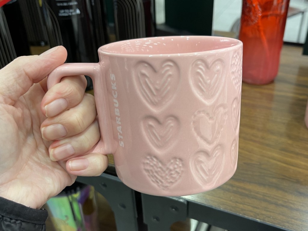 hand holding pink heart mug in store
