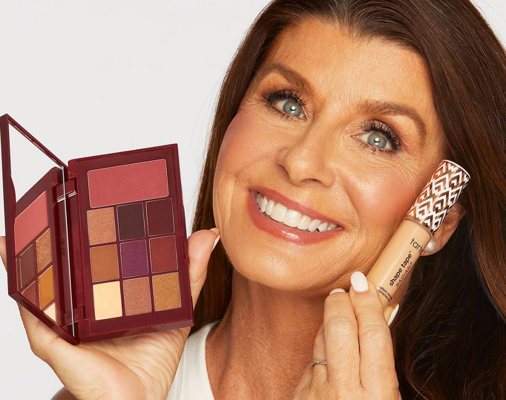 woman holding a tarte eyeshadow palette and shape tape up next to her face