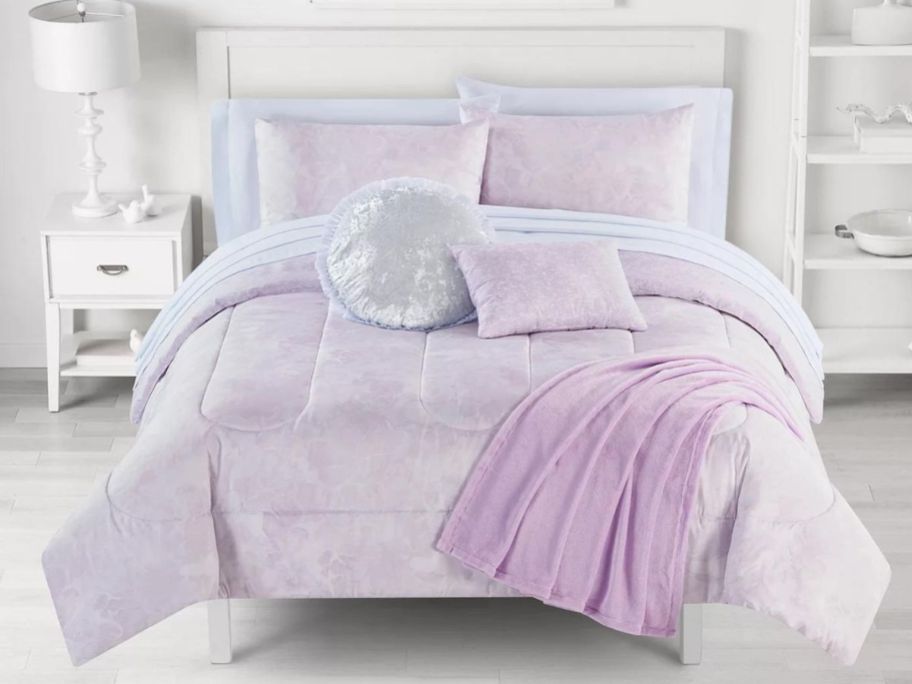 A bedroom with a purple comforter on the bed
