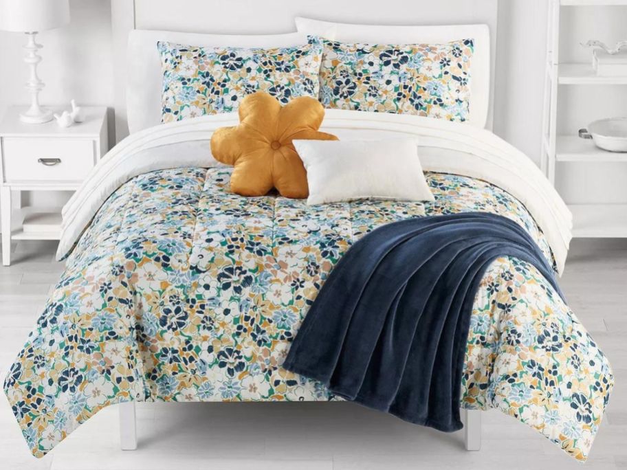 A bedroom with a flowery comforter on the bed