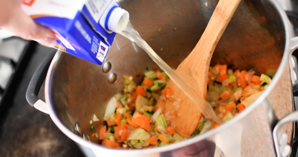 adding broth to minestrone soup