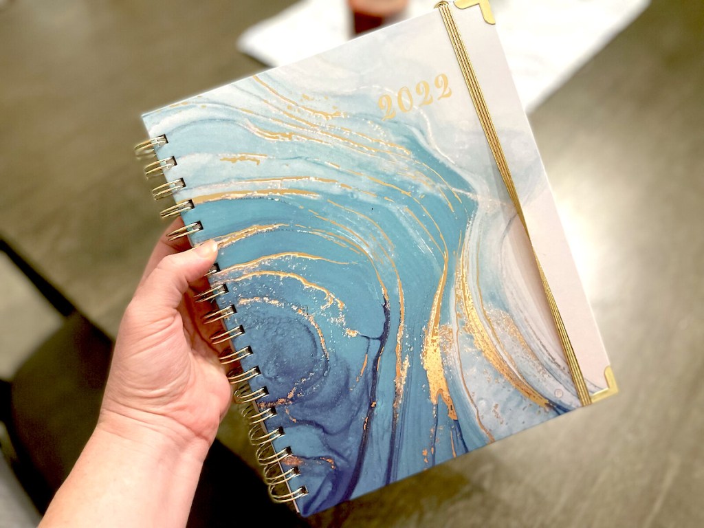 hand holding a 2022 blue gold and white planner