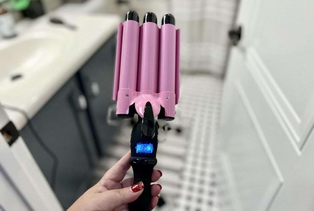 hand holding pink and black curling wand