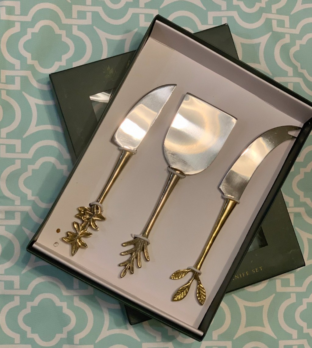 box of gold leaf cheese knives in box on patterned table 