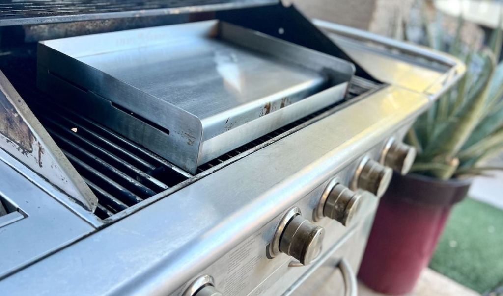 stainless steel griddle on top of grill outside