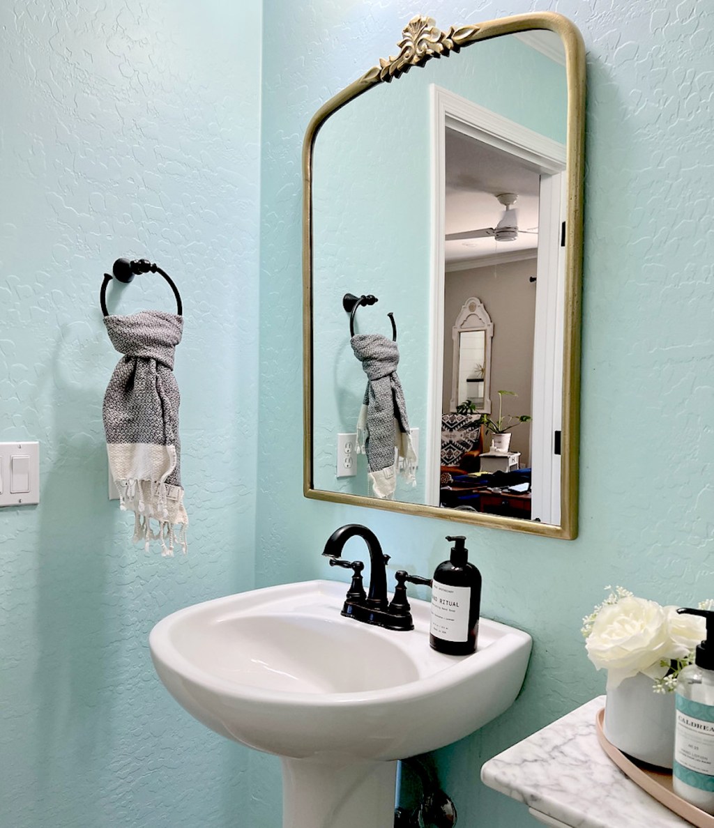 small bathroom vanity with gold vintage anthropologie mirror dupe hanging on wall