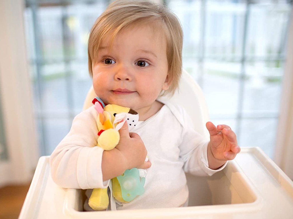 baby in high chair holding soft toy