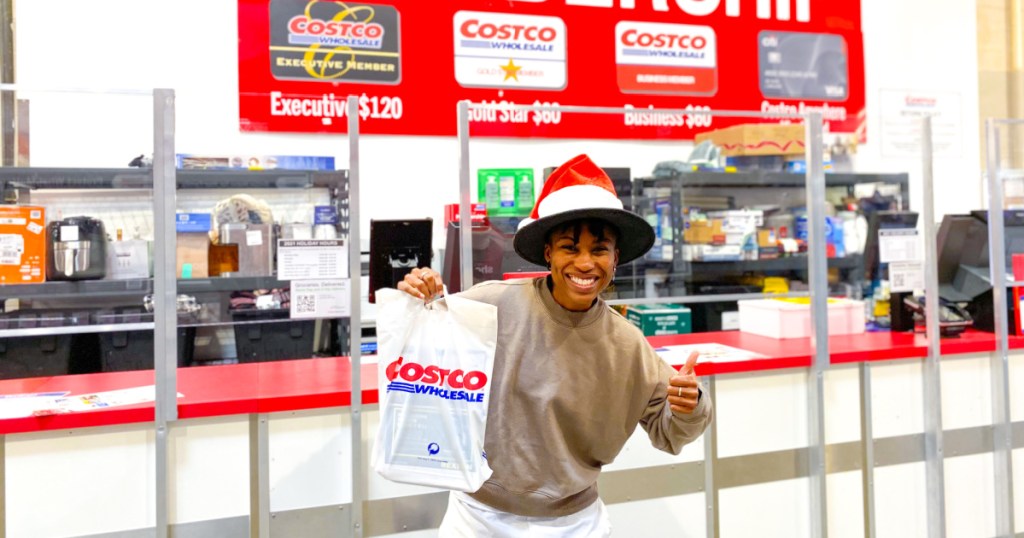 woman holding a Costco bag in front of the Costco membership counter