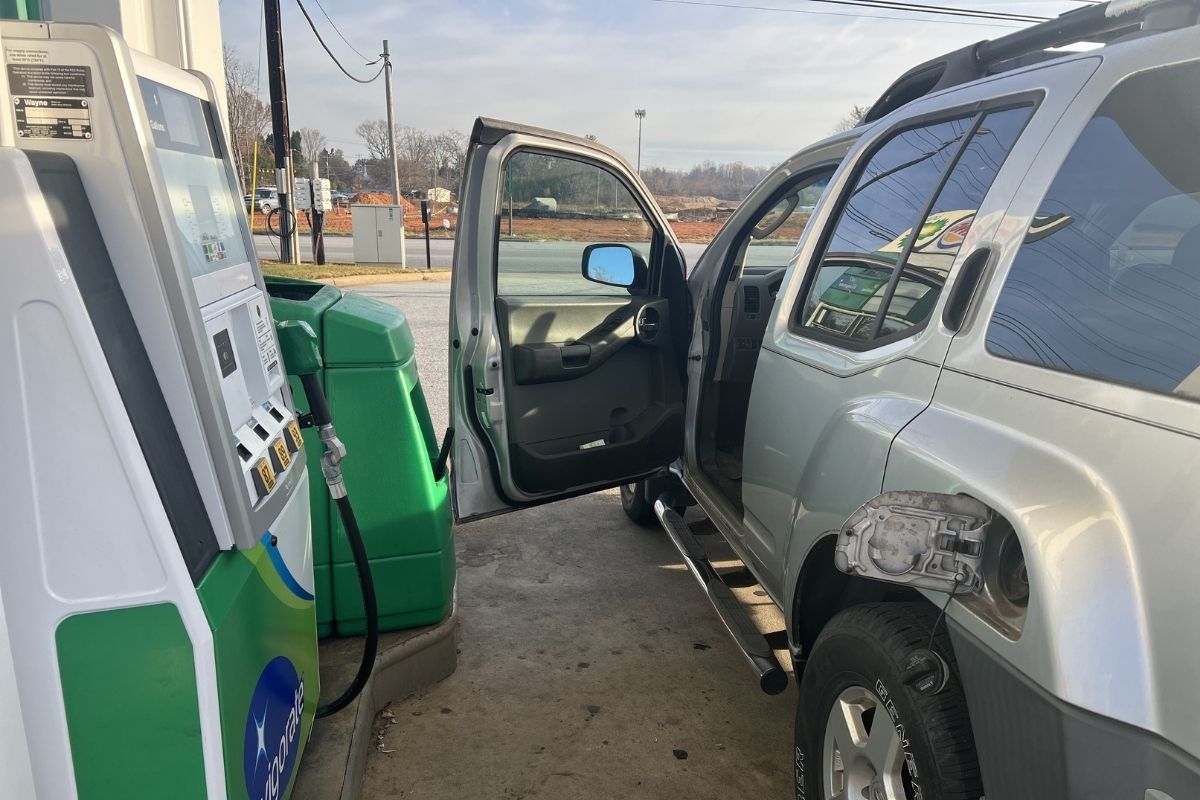 car with door open parked at BP gas pump