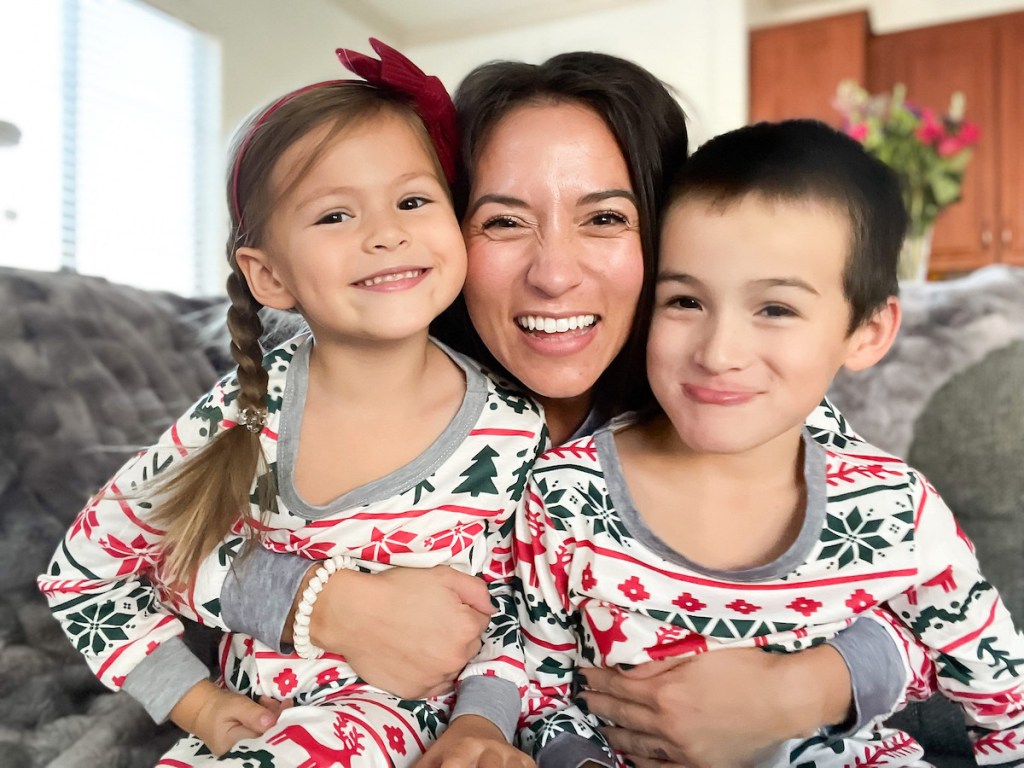 woman holding two kids on her lap smiling