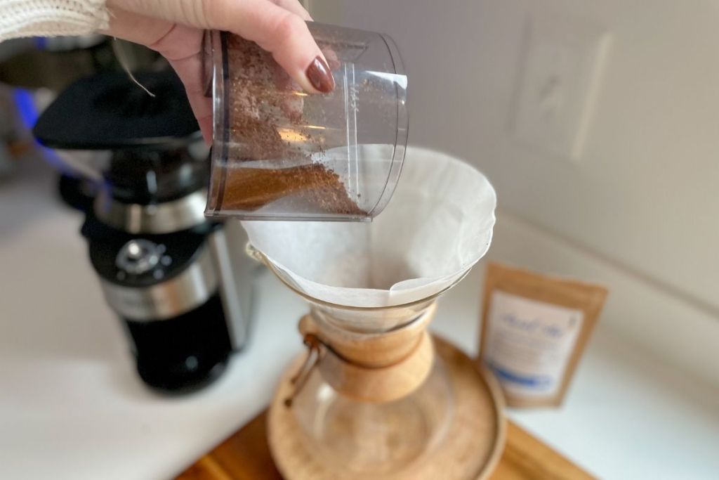 pouring ground coffee into a Chemex coffee maker