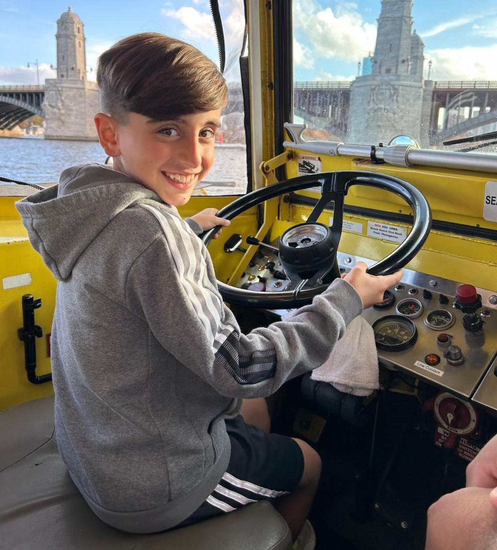 boy driving duck boat tour on water