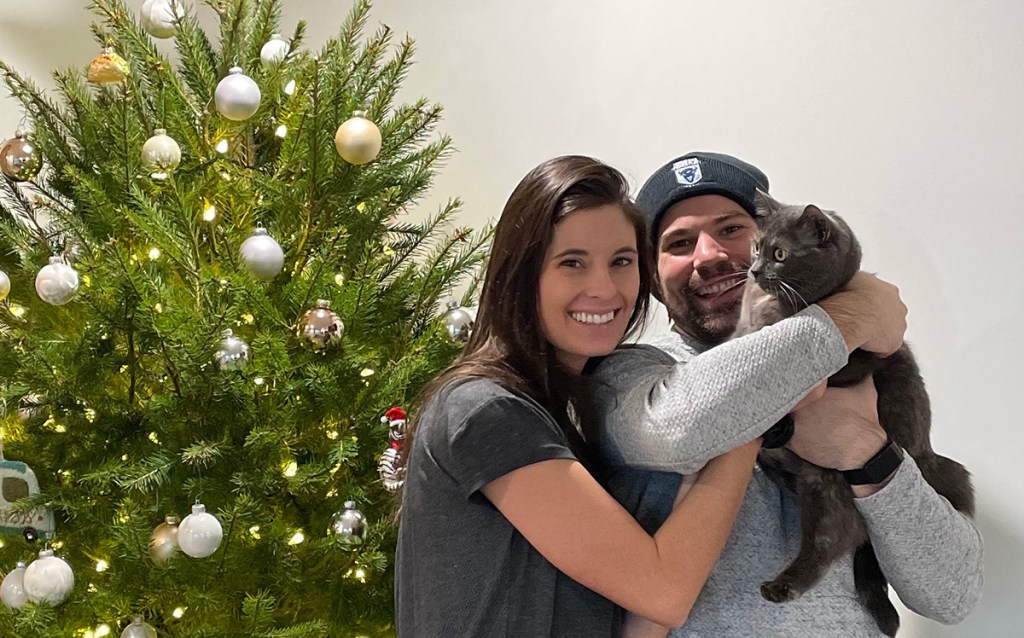 woman with man and cat in front of Christmas tree