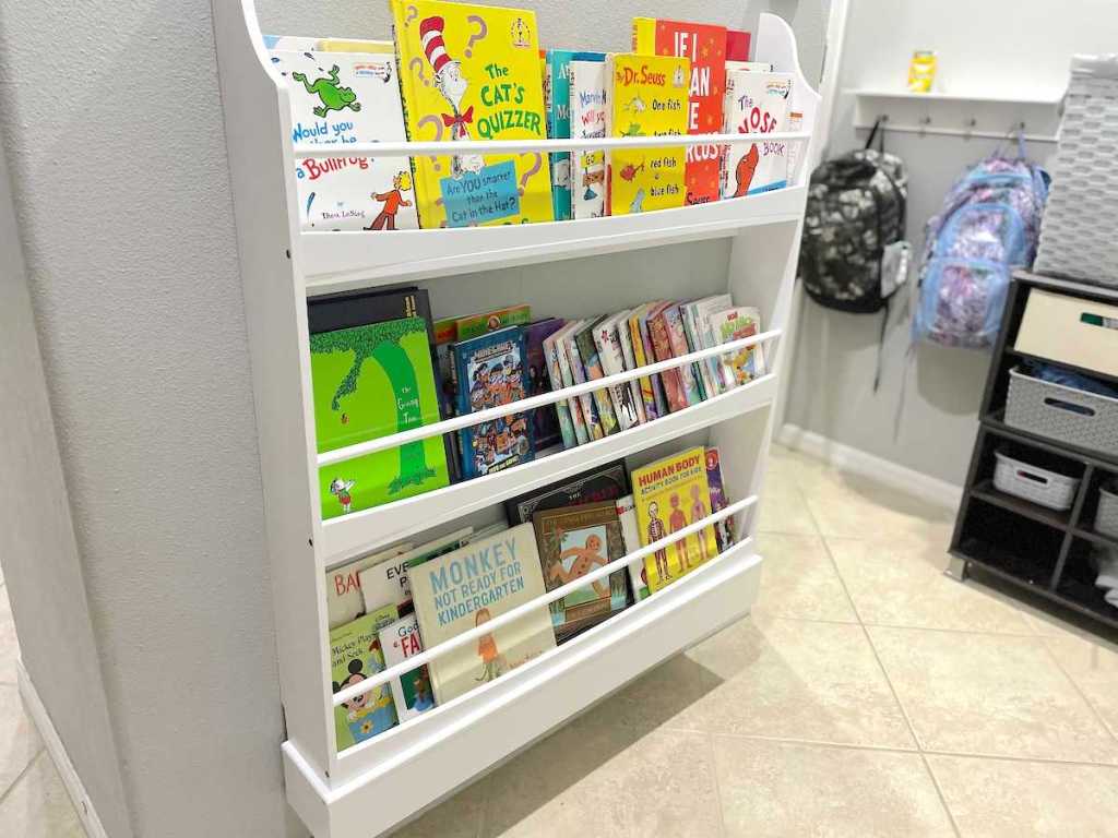 white bookshelf on wall with various kids books stacked on shelves