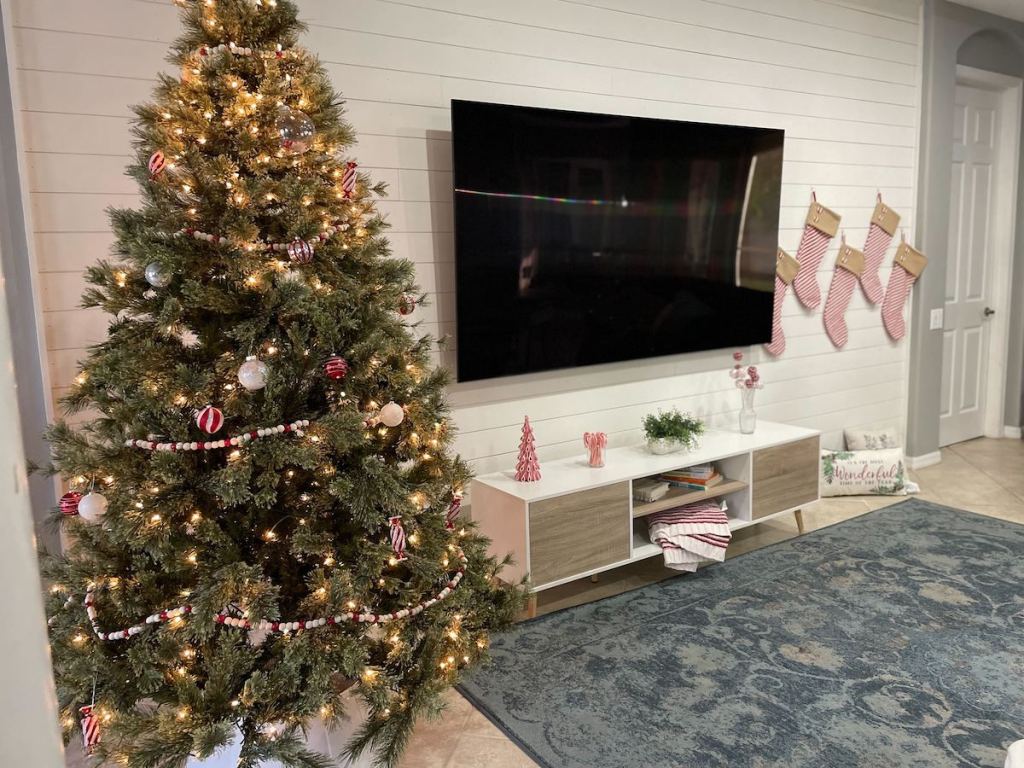 living room with christmas tree tv and stockings on wall