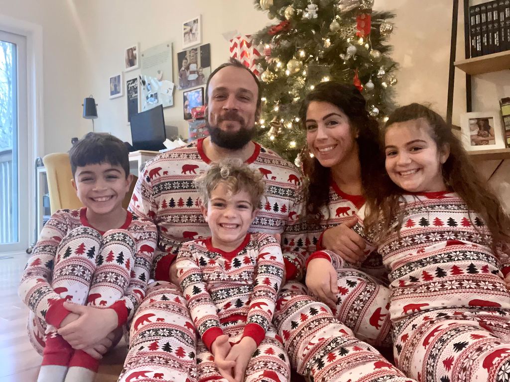 family wearing matching Christmas jammies in front of tree