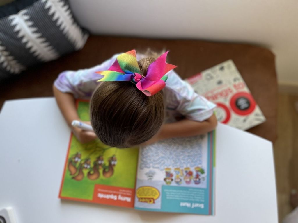 little girl doing puzzles in Highlights magazine