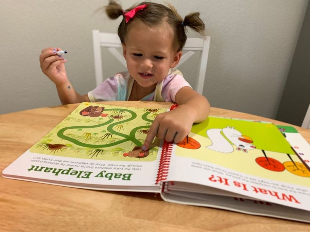 girl sitting at table writing in highlights magazine on table