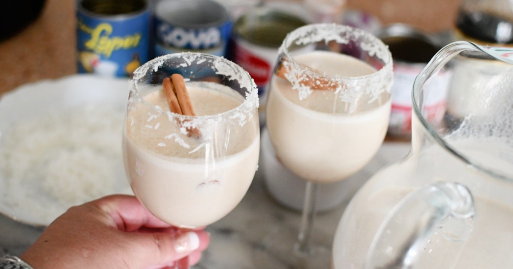 holding glasses of coconut coquito