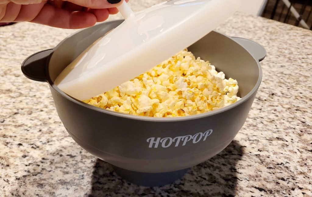 hand holding clear white lid over hotpop popcorn maker