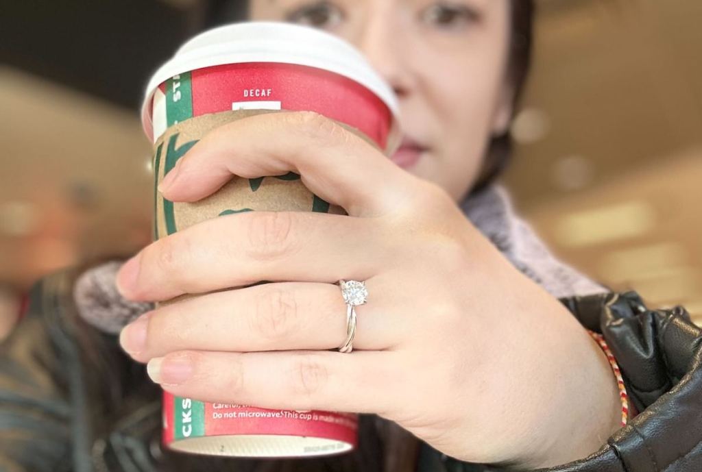 close up of woman holding starbucks cup wearing engagement ring