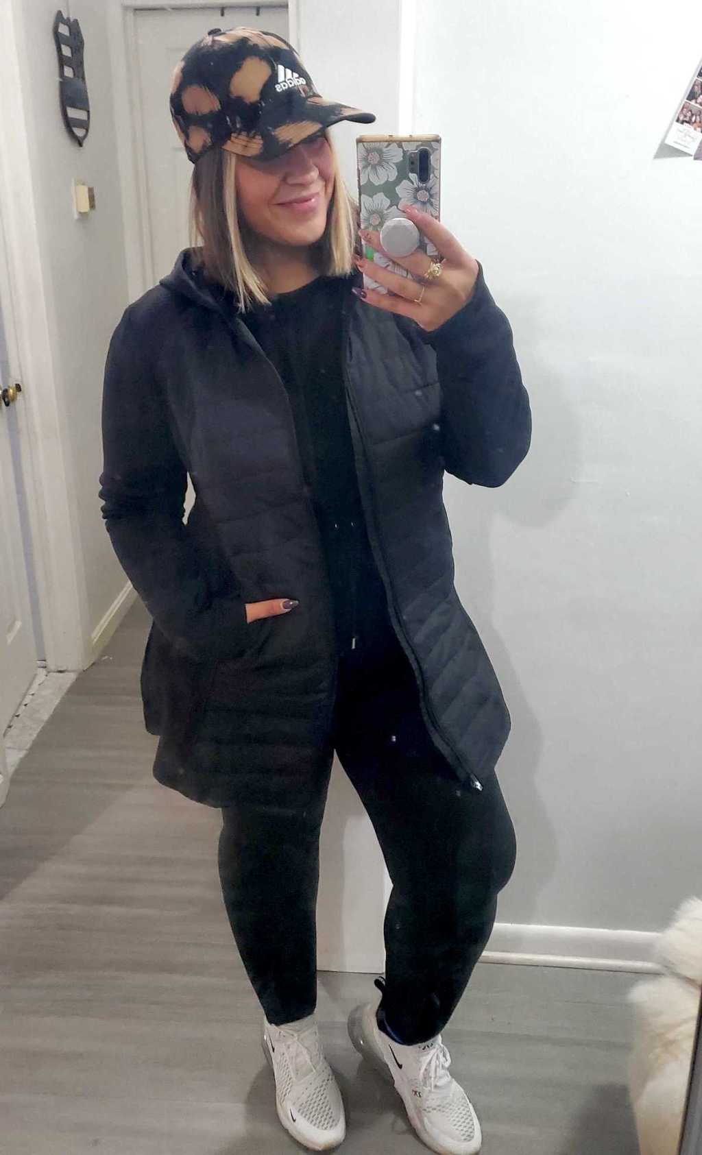 woman taking selfie with black parka jacket and adidas hat 