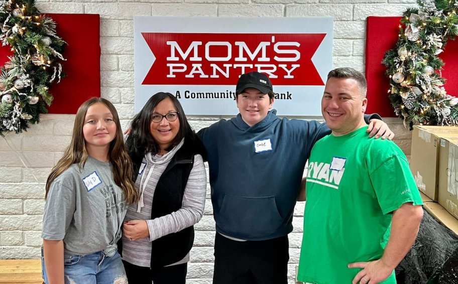 family standing together in front of food pantry sign