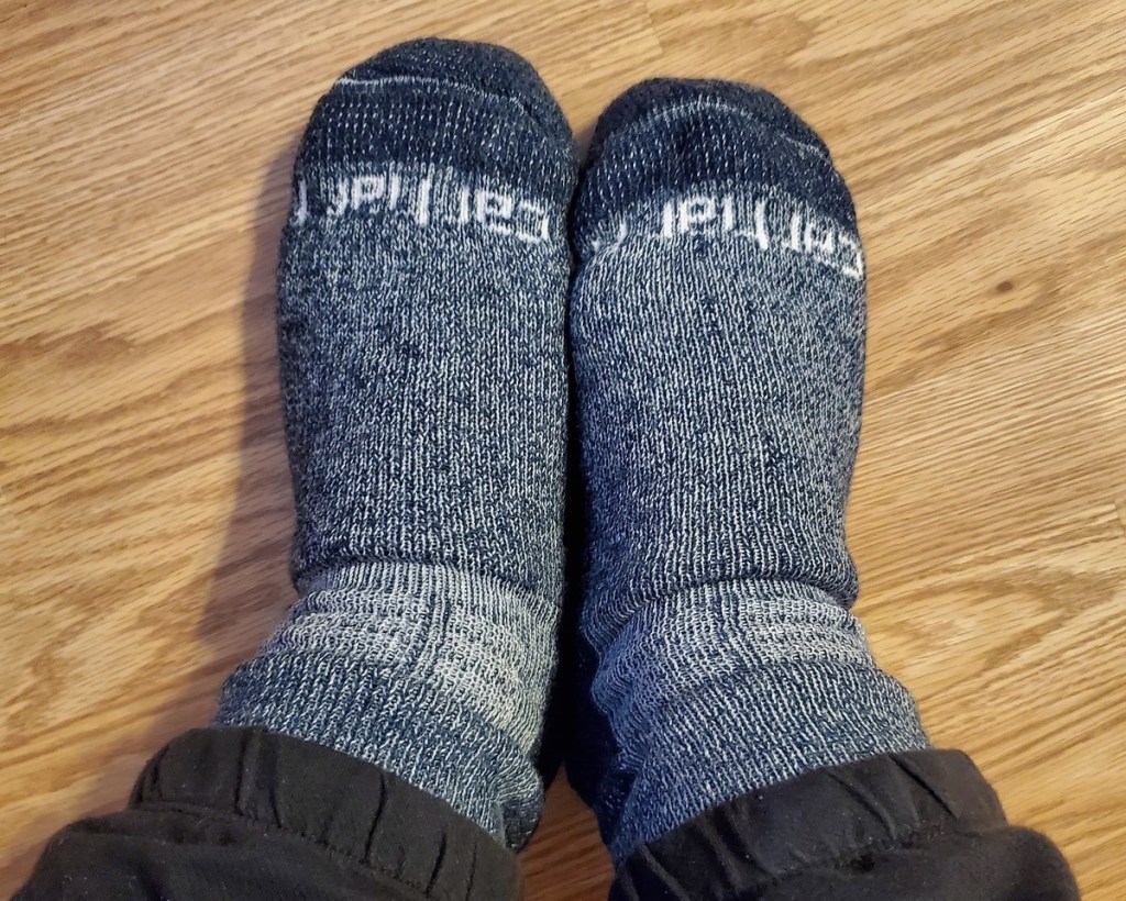 pair of feet with blue carhartt socks on wood floor