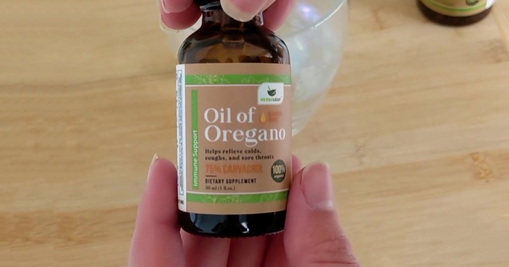 hand holding a bottle of oil of oregano