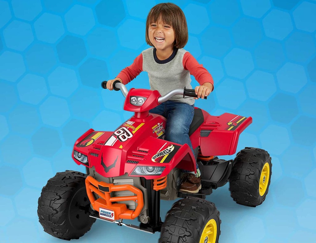 young boy sitting on a power wheels hot wheels ride on atv