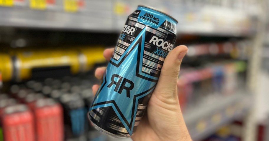 hand holding up a can of rockstar energy in front of a walmart shelf