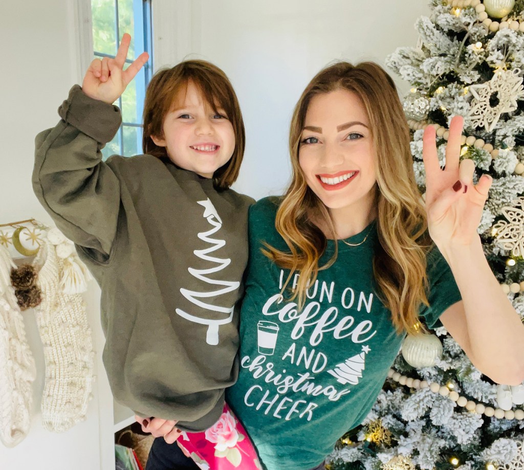 woman and daughter wearing Christmas shirts in front of Christmas tree
