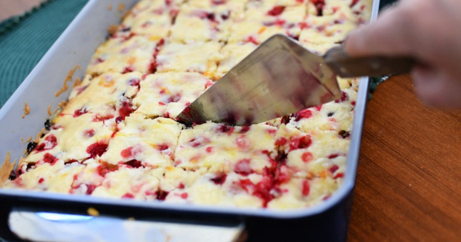 slicing a cranberry christmas cake