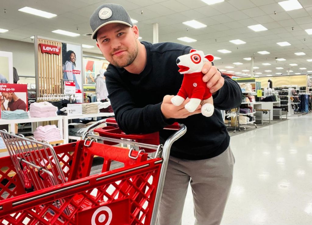 man holding a target dog while leaning on target red cart