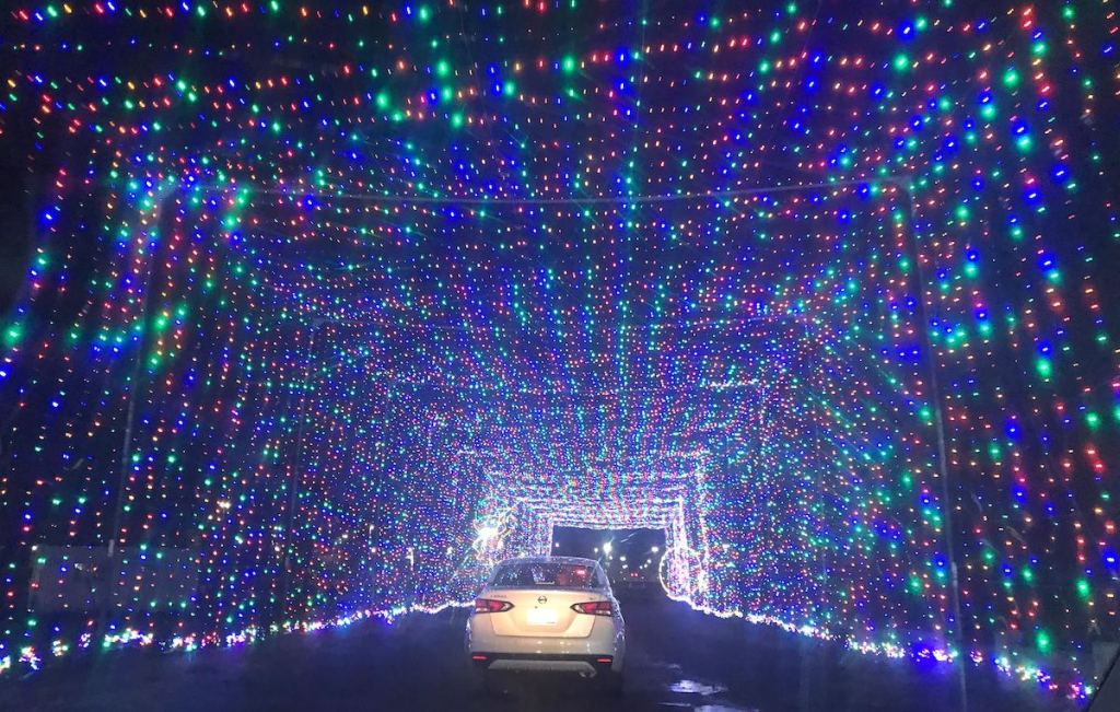 car driving through tunnel of colored christmas lights