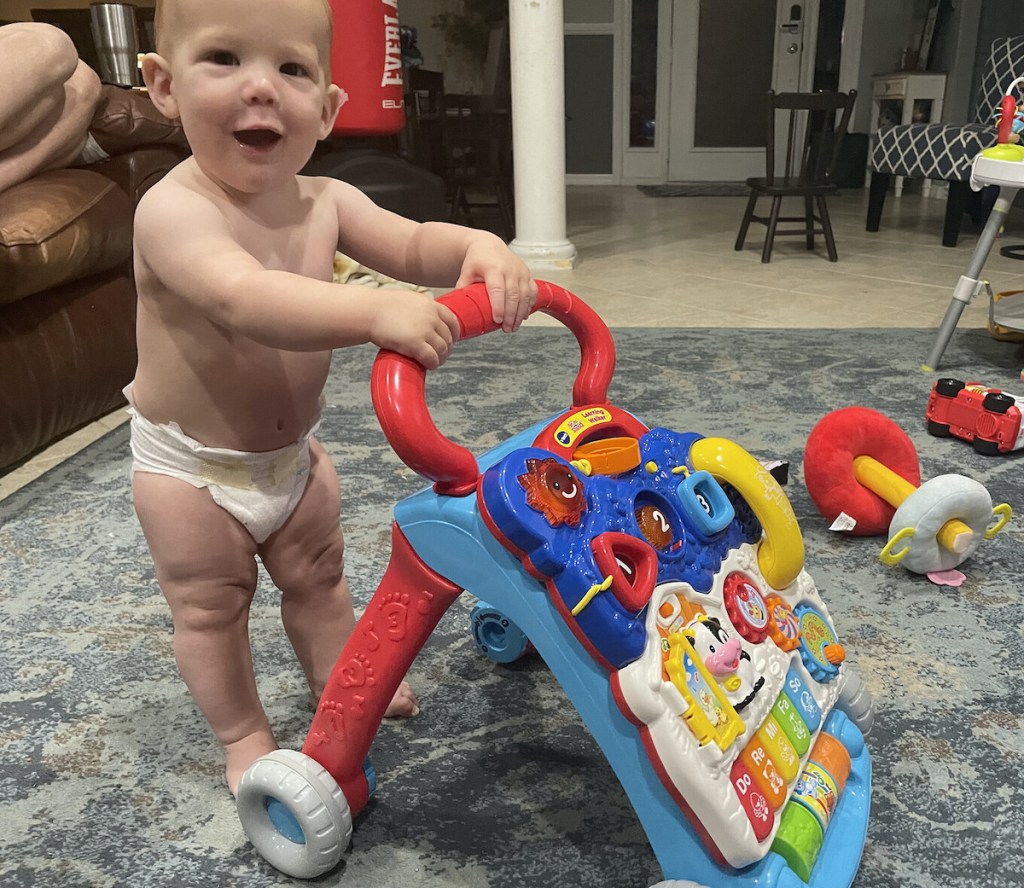 baby boy standing on floor with baby walker 