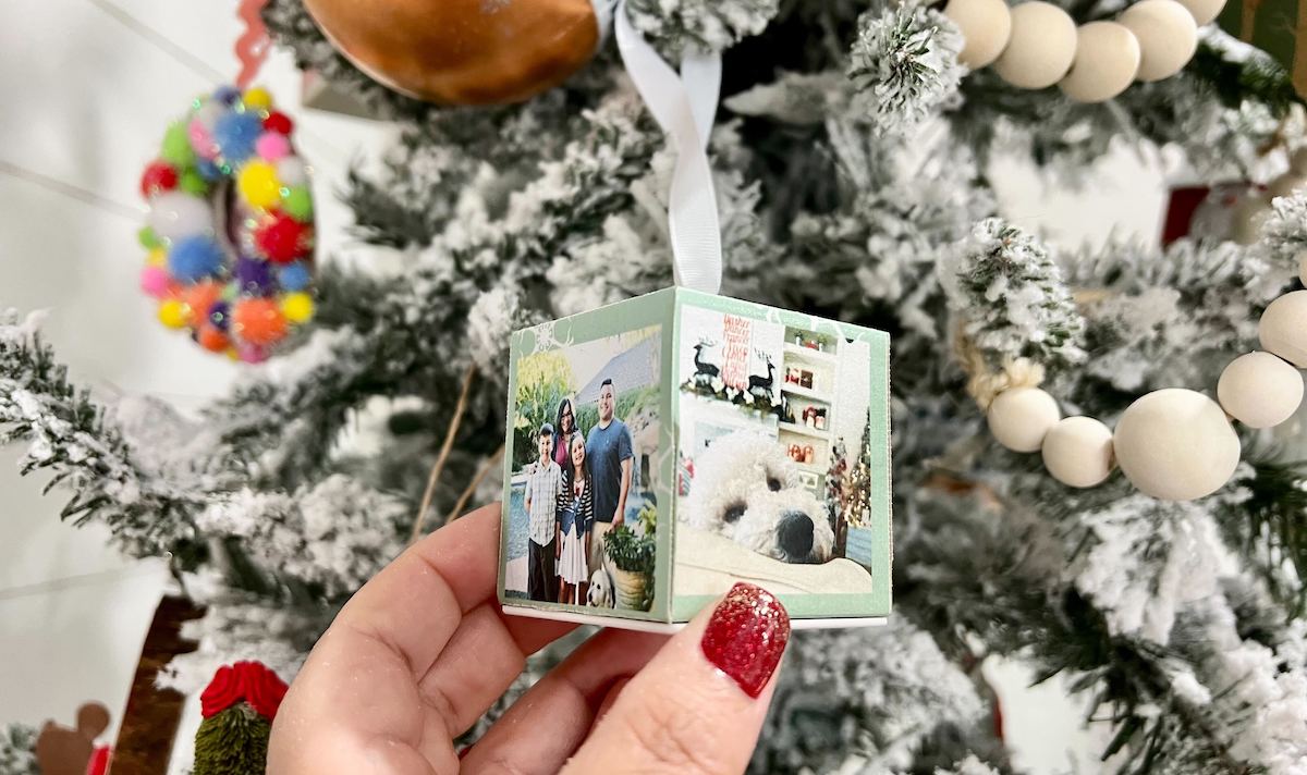 hand holding a cube shaped ornament with photos on the outside