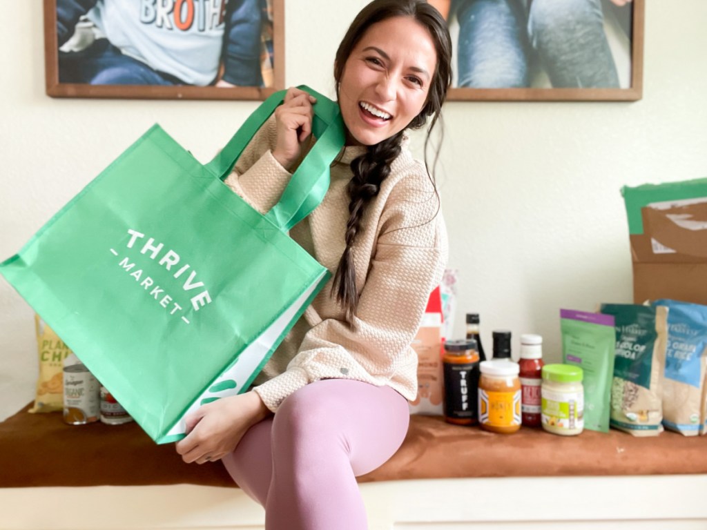 woman sitting on bench holding thrive market bag