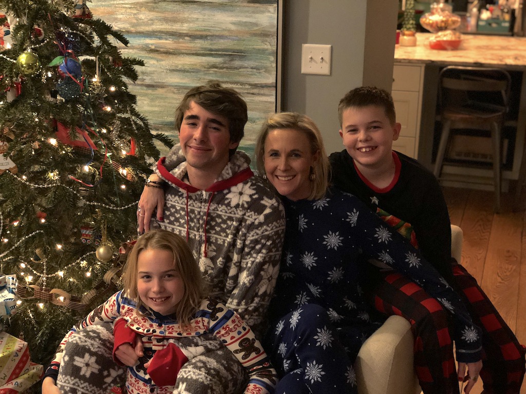 woman with kids in pajamas by Christmas tree 