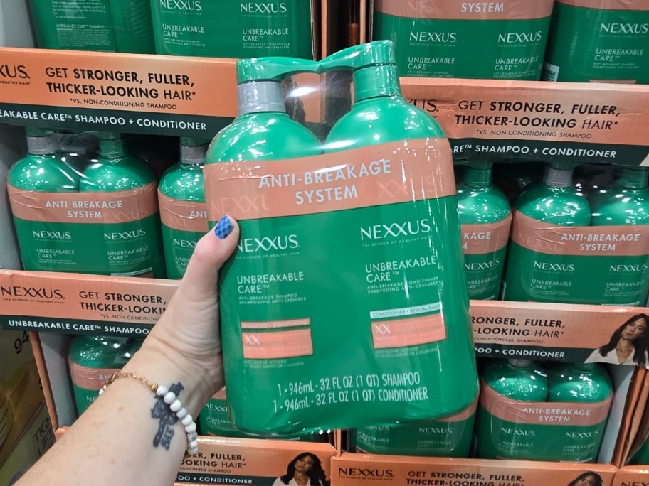 hand holding a large wrapped Nexxus Unbreakable Care Shampoo & Conditioner bottle set at Costco